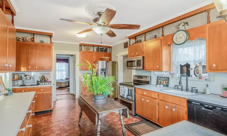 Kitchen with a sink, light countertops, ornamental molding, appliances with stainless steel finishes, and open shelves