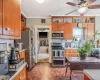 Kitchen with visible vents, ornamental molding, brick floor, brown cabinetry, and stainless steel appliances