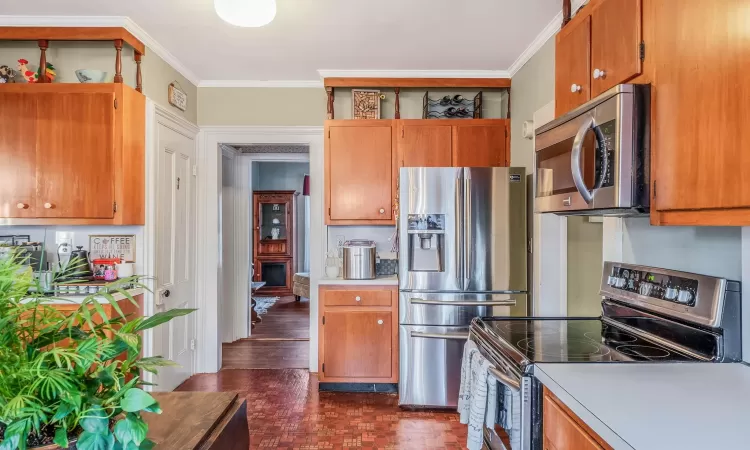 Kitchen featuring appliances with stainless steel finishes, light countertops, and crown molding