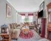 Living room with wood finished floors, ornamental molding, and wallpapered walls