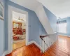 Hallway featuring an upstairs landing, baseboards, and wood-type flooring