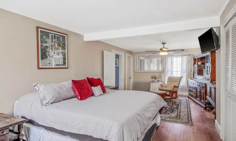 Bedroom with dark wood finished floors, radiator, crown molding, and a ceiling fan