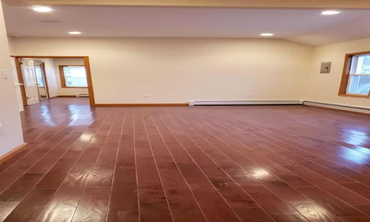 living room with a baseboard heating unit, lofted ceiling, and dark wood-type flooring