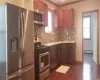 Kitchen #1  featuring appliances with stainless steel finishes, backsplash, dark wood-type flooring, a baseboard heating unit, and sink