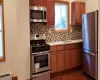 Kitchen featuring sink, baseboard heating, dark hardwood / wood-style floors, backsplash, and appliances with stainless steel finishes