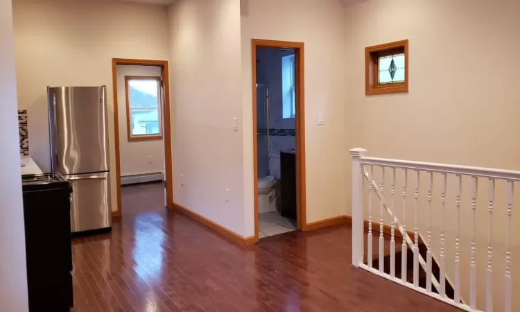 Corridor featuring dark wood-type flooring and a baseboard radiator