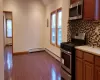 Kitchen with lofted ceiling, tasteful backsplash, a baseboard radiator, dark hardwood / wood-style flooring, and stainless steel appliances