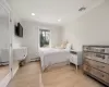 Bedroom featuring a baseboard heating unit, light wood-style flooring, visible vents, and ornamental molding