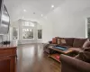 Living area featuring dark wood-style floors, a wainscoted wall, recessed lighting, and vaulted ceiling