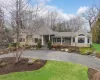 View of front facade with a front yard, stone siding, driveway, and a shingled roof