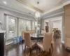 Dining space featuring dark wood-type flooring, a notable chandelier, ornamental molding, a baseboard radiator, and a raised ceiling