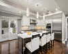 Kitchen featuring a kitchen breakfast bar, wall chimney exhaust hood, dark wood-style floors, and stainless steel appliances