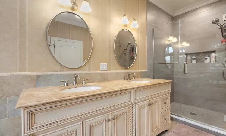 Bathroom with crown molding, a shower stall, and a sink