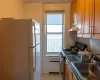 Kitchen featuring freestanding refrigerator, a sink, under cabinet range hood, stainless steel gas range oven, and backsplash