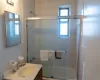 Full bath featuring bath / shower combo with glass door, tile walls, and vanity