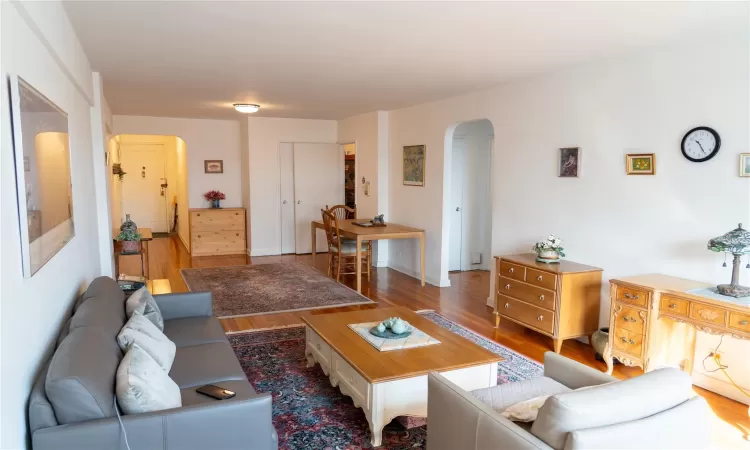 Living room with arched walkways, baseboards, and wood finished floors