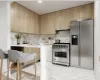 Kitchen featuring decorative backsplash, light brown cabinets, and appliances with stainless steel finishes