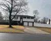 Split foyer home featuring driveway, an attached garage, and fence