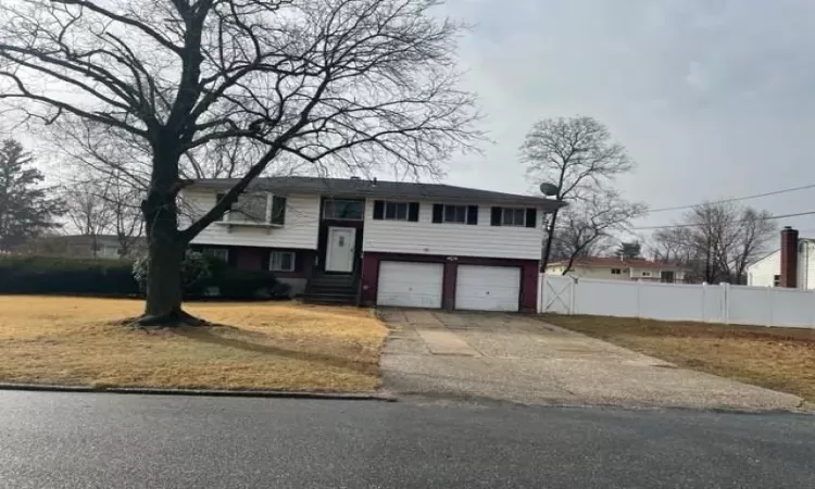 Split foyer home featuring driveway, an attached garage, and fence