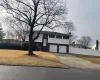 Bi-level home featuring a garage, driveway, and fence