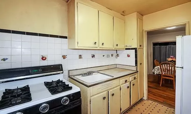 Kitchen featuring white appliances, backsplash, and a sink