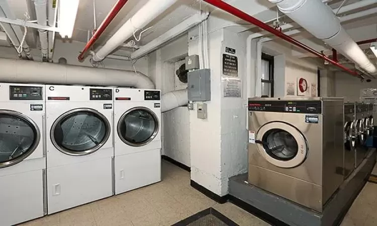 Community laundry room featuring tile patterned floors, electric panel, and independent washer and dryer