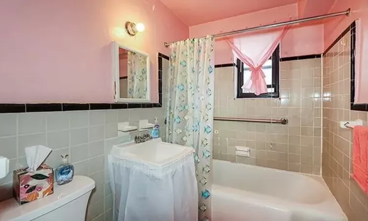 Bathroom featuring vanity, shower / bath combination with curtain, toilet, and tile walls