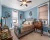 Carpeted bedroom with crown molding, baseboards, radiator heating unit, cooling unit, and a ceiling fan