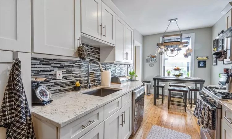 Kitchen with tasteful backsplash, light wood-style floors, stainless steel appliances, and a sink