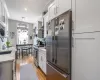 Kitchen featuring a sink, white cabinetry, stainless steel appliances, wall chimney exhaust hood, and light wood finished floors