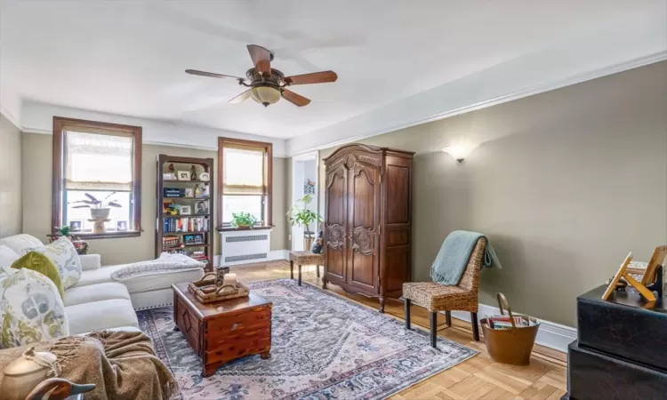 Living room featuring baseboards, a ceiling fan, and radiator heating unit