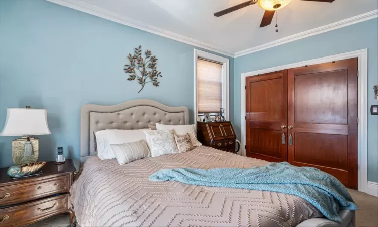 Carpeted bedroom featuring crown molding and ceiling fan