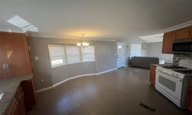 Kitchen featuring stainless steel microwave, visible vents, white gas range oven, and a wealth of natural light