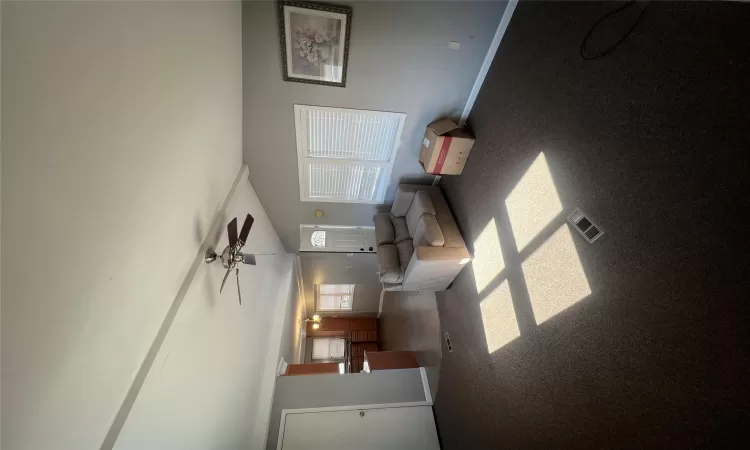 Unfurnished living room with dark colored carpet, visible vents, baseboards, and vaulted ceiling