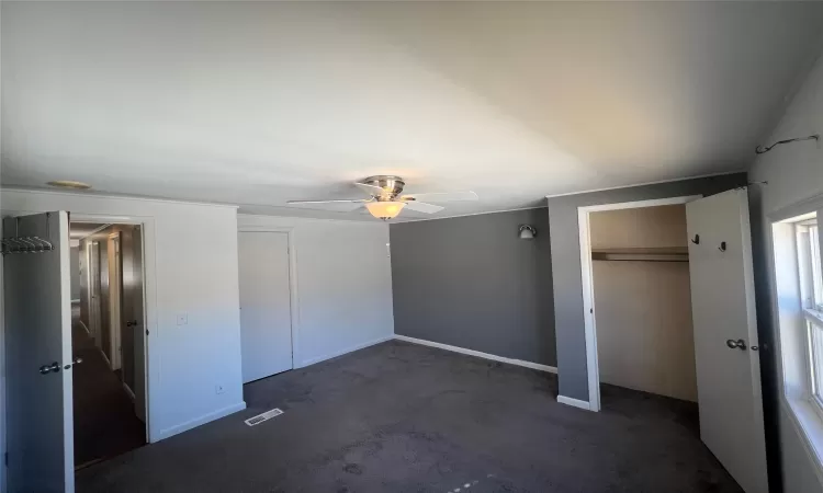 Unfurnished bedroom with a ceiling fan, visible vents, and baseboards