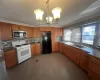 Kitchen with an inviting chandelier, white range with gas cooktop, freestanding refrigerator, a sink, and stainless steel microwave