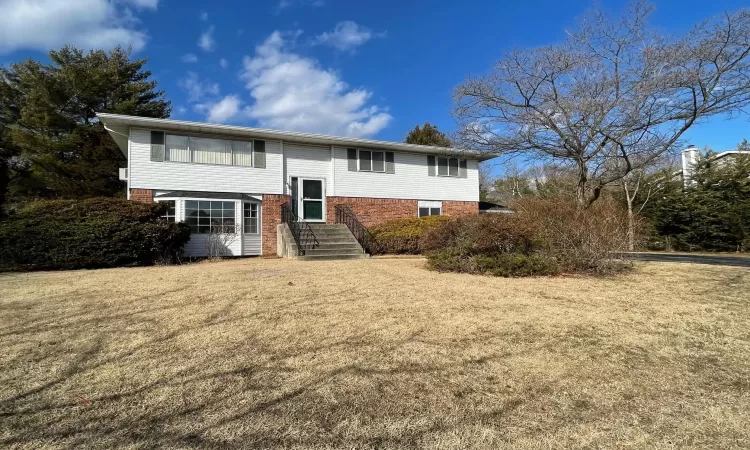 View of front facade with entry steps, a front yard, and brick siding