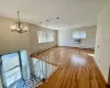 Unfurnished living room featuring an AC wall unit, wood finished floors, an inviting chandelier, baseboards, and baseboard heating