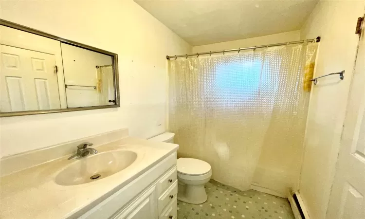 Bathroom with vanity, curtained shower, toilet, and a baseboard heating unit