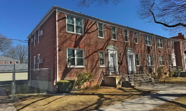 View of front of property featuring fence, brick siding, and a gate