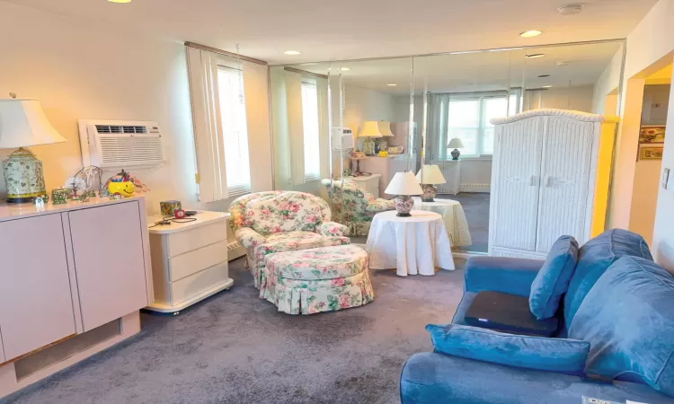 Living room featuring a wall mounted air conditioner, recessed lighting, and carpet floors