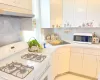 Kitchen with a sink, white appliances, under cabinet range hood, and light countertops