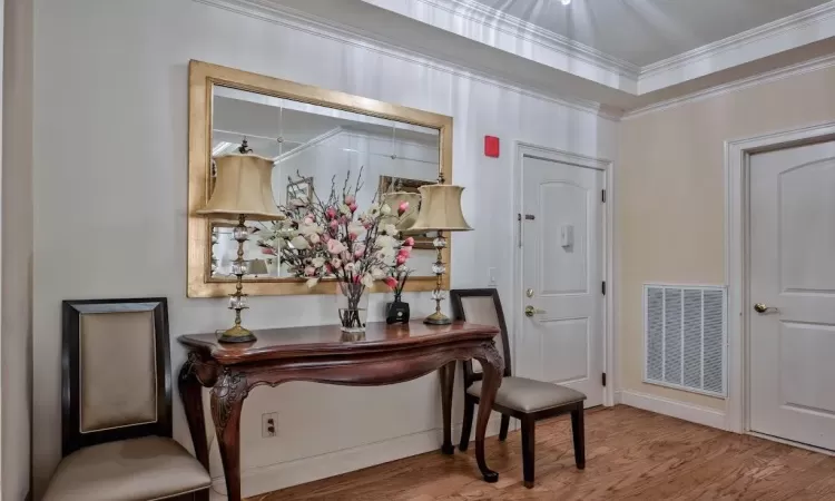 Entrance foyer with visible vents, wood finished floors, and crown molding