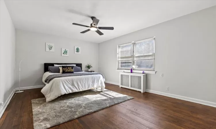 Bedroom with ceiling fan, baseboards, radiator, and wood finished floors