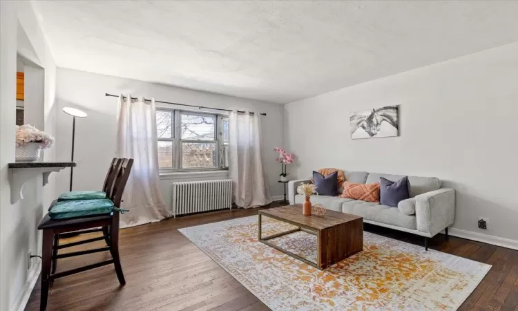 Living area with radiator, a textured ceiling, baseboards, and hardwood / wood-style floors