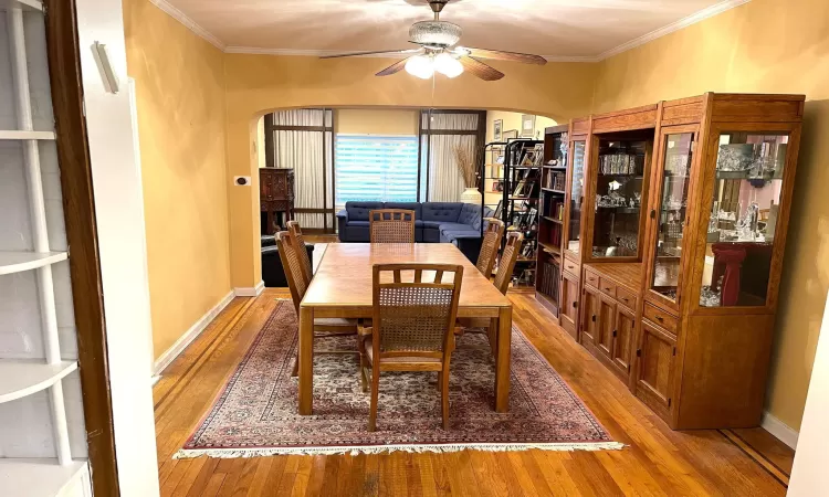 Dining space with hardwood / wood-style floors, arched walkways, and ornamental molding