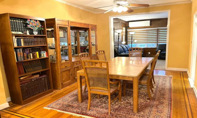 Dining area with hardwood / wood-style floors, an AC wall unit, ornamental molding, and a ceiling fan