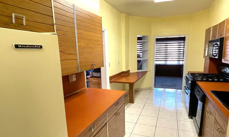 Kitchen with light tile patterned flooring and black appliances