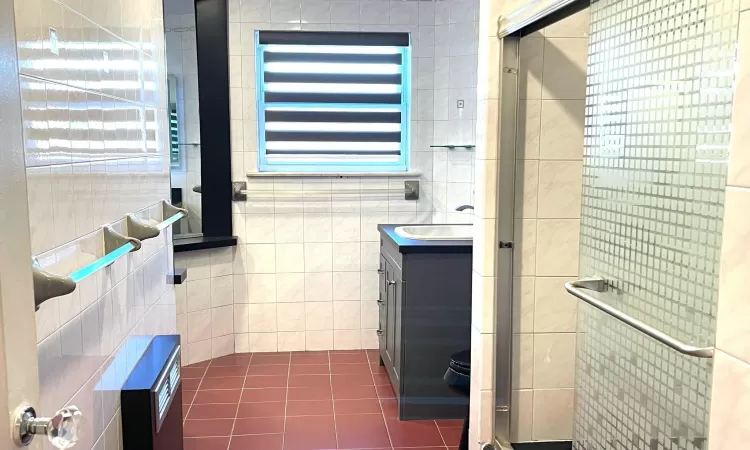 Full bathroom featuring tile patterned flooring, tile walls, vanity, and a shower stall