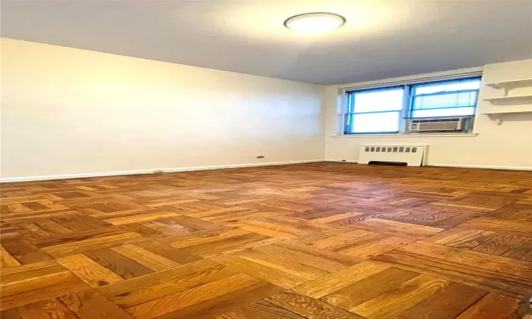 Unfurnished room featuring cooling unit, baseboards, and radiator